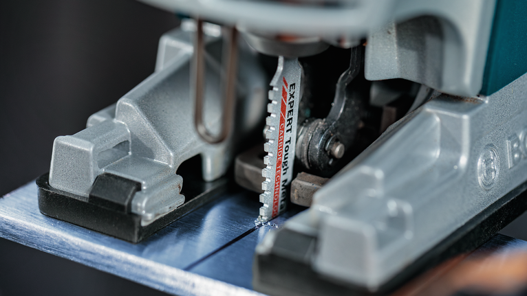 超耐久超厚金屬專業款 T155HHM 線鋸片,3 件 拼圖鋸刀片切割金屬板的特寫。