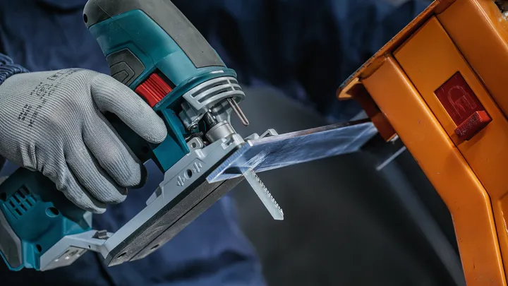 Object #200559118: 7478951_app_web_08 一名佩戴安全設備的人使用曲線鋸切割透明塑膠片。