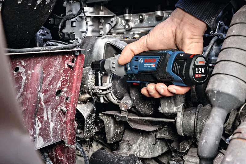 一個人使用無線棘輪扳手緊固引擎室內的螺栓。.