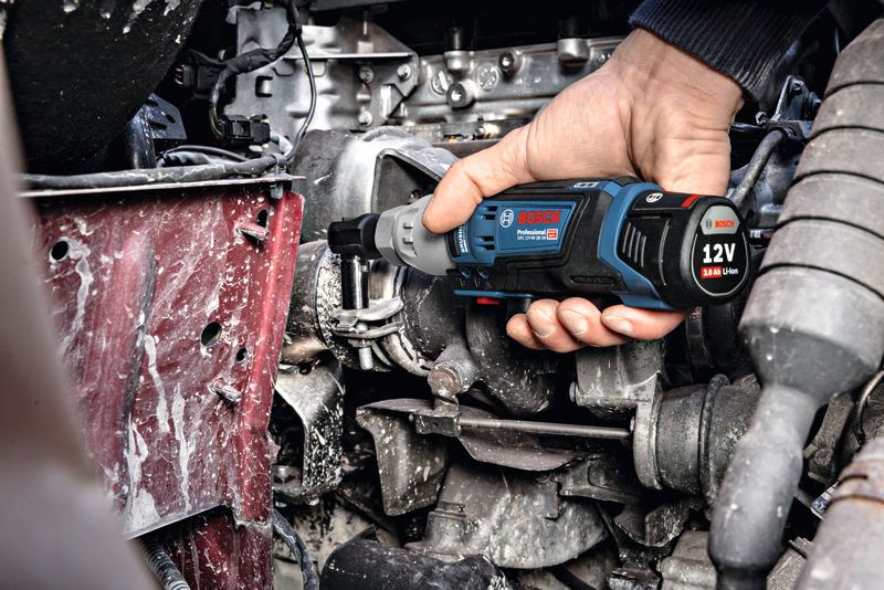 一個人使用無線棘輪扳手緊固引擎室內的螺栓。.