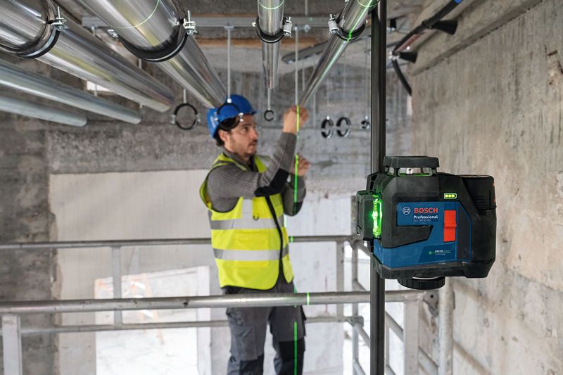 一名配戴安全設備的人員使用雷射調平工具對準管道。.