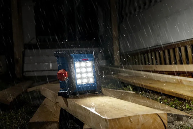 大雨中，建築工地上的無線工地燈照亮了木板。.