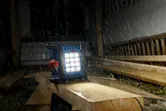 大雨中，建築工地上的無線工地燈照亮了木板。.