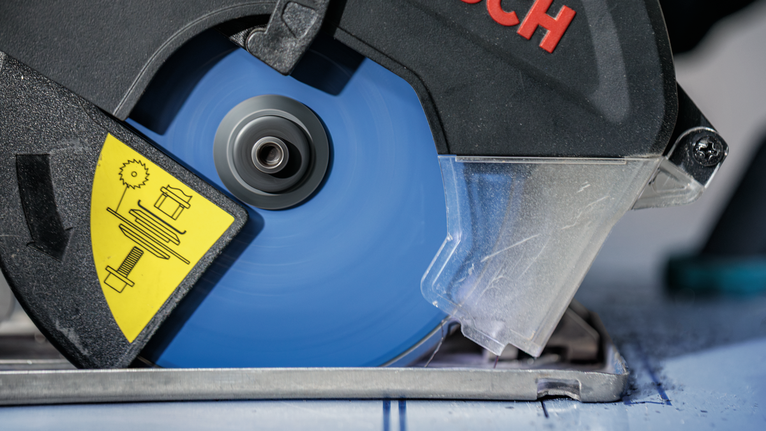 帶有藍色刀片的圓鋸切割一塊有標記的材料。.
