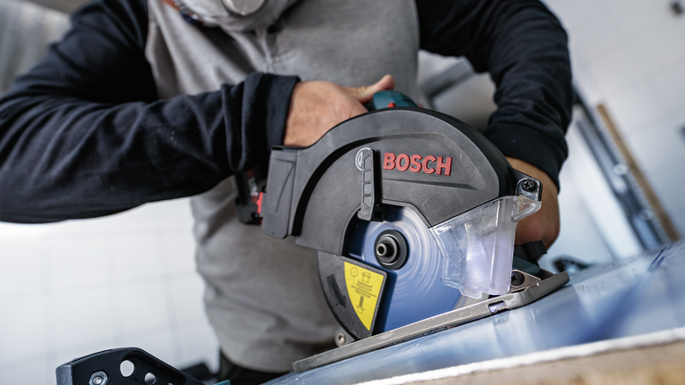 配戴安全設備的人員用圓鋸切割金屬板。.