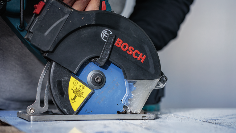 一名配戴安全設備的人員使用圓鋸切割一塊材料。.