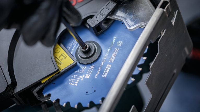 配戴安全設備的人員使用手動工具擰緊圓鋸片。.