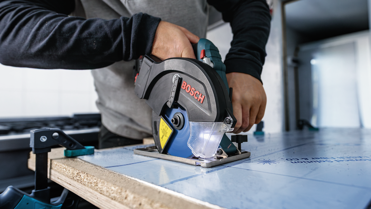 操作圓鋸切割夾在工作台上的木板的人。.