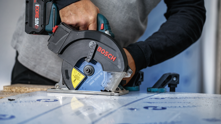 配戴安全設備的人員使用圓鋸切割層壓板。.