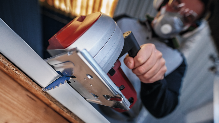 一名穿戴安全裝備的人員用圓鋸切割木板。