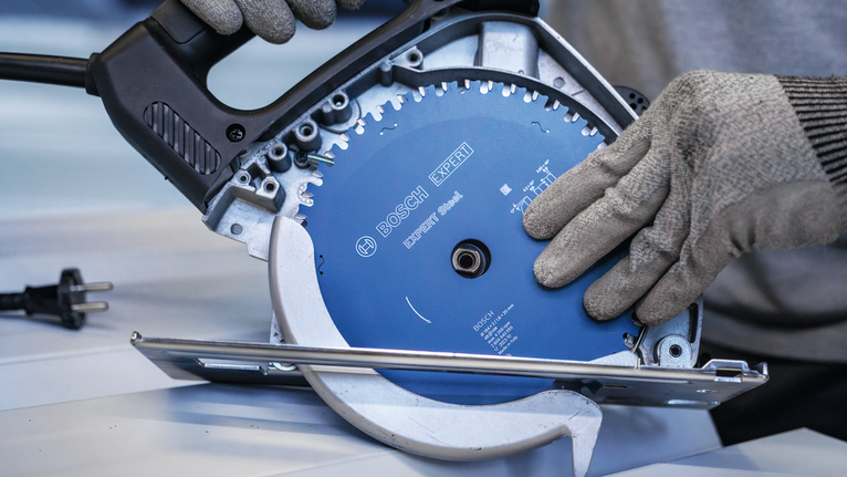 穿戴安全裝備的人員將圓鋸片固定在電動工具上。