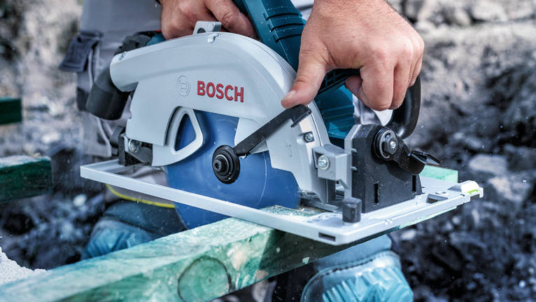 配戴安全設備的人員使用圓鋸切割木材。.