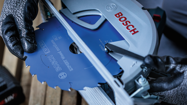 配戴安全設備的人員將圓鋸片安裝到電動工具中。.