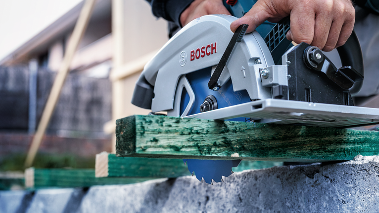 配戴安全設備的人員使用圓鋸切割綠木。.