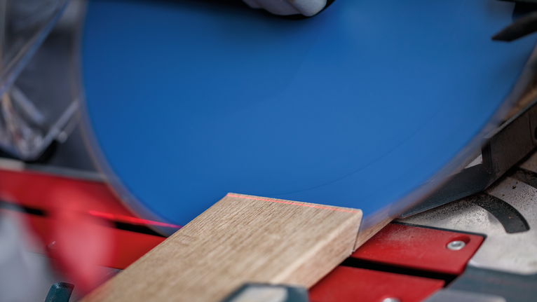 配戴安全設備的人員在圓鋸上切割木板。.