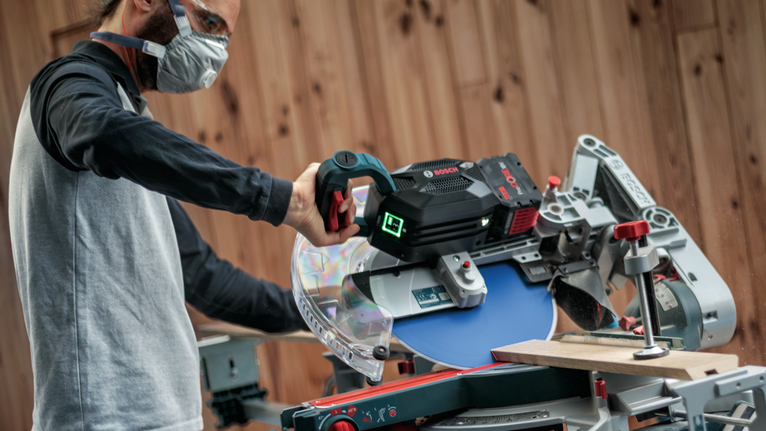 配戴安全設備的人員操作斜切鋸切割木板。.