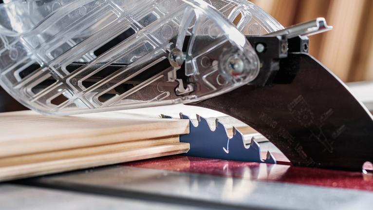 帶有防護裝置的台鋸可以對木頭進行精確切割。.