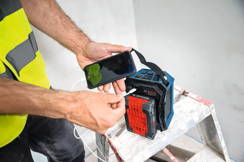 一名佩戴安全設備的人將智慧型手機連接到梯子上的便攜式藍牙揚聲器。.