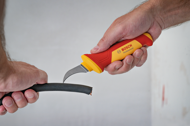 有人用絕緣刀剝去粗電纜的外層絕緣層。