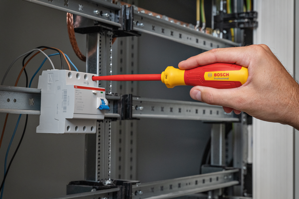 使用絕緣螺絲起子在配電盤上安裝電氣元件的人員。