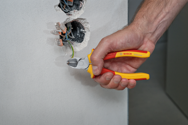 有人用絕緣鉗剪斷牆壁插座上的電線。