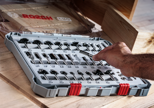 人們從木製工作台上整齊排列的鑽頭中選擇一個路由器鑽頭。.