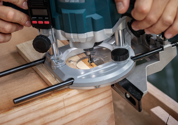 一個人使用鑿子銑刀在一塊木頭上鑿出凹槽。.