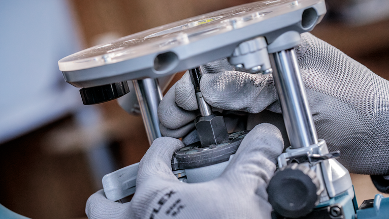 一名佩戴安全設備的人員在車間對電動工具進行一些調整。.