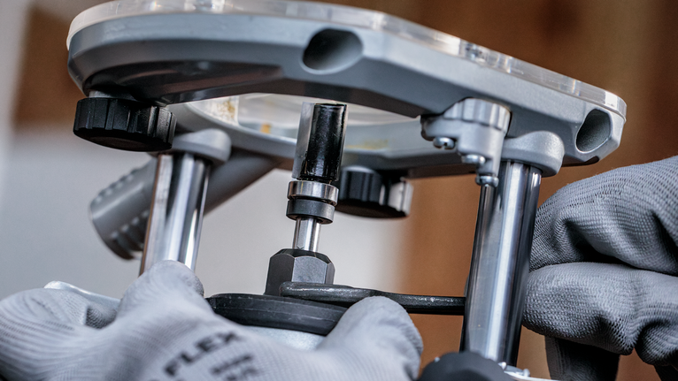 配戴安全設備的人員正在調整金屬路由器工具。.