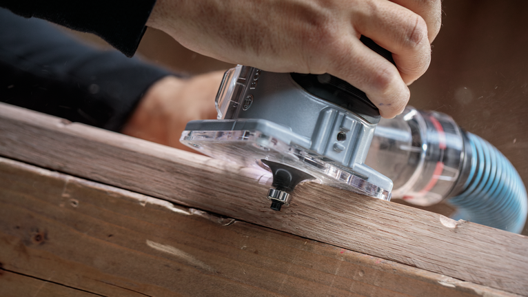 人們使用手持式路由器來塑造木板的邊緣。.