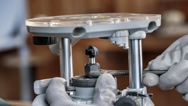 配戴安全設備的人員使用扳手調整路由器工具。.