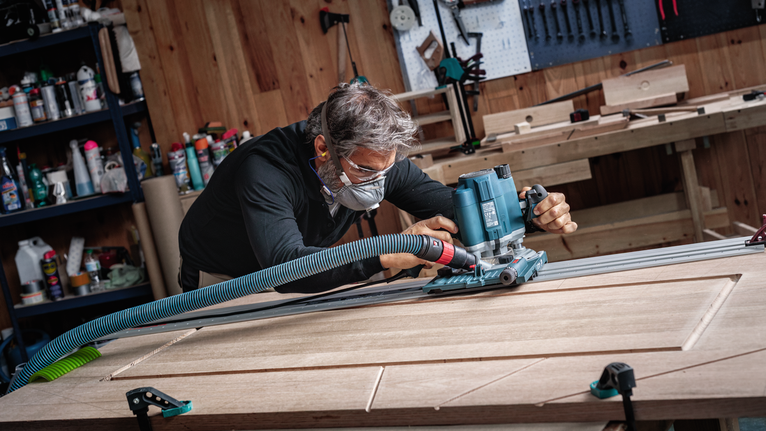 配戴安全設備的人員使用電動工具在木門上開槽。.