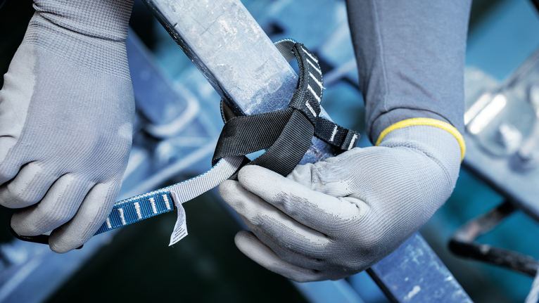 配戴安全設備的人員將安全帶固定在金屬欄桿上。.