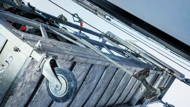 一名配戴安全設備的人員使用鑽頭對金屬結構進行鑽探。.