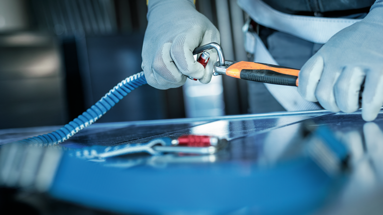 配戴安全設備的人員將登山扣固定在安全帶上。.