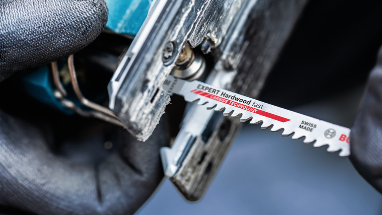 配戴安全設備的人員將曲線鋸刀片插入電動工具。.