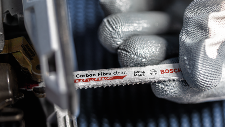 配戴安全設備的人員將碳纖維鋸片安裝到電動工具中。.