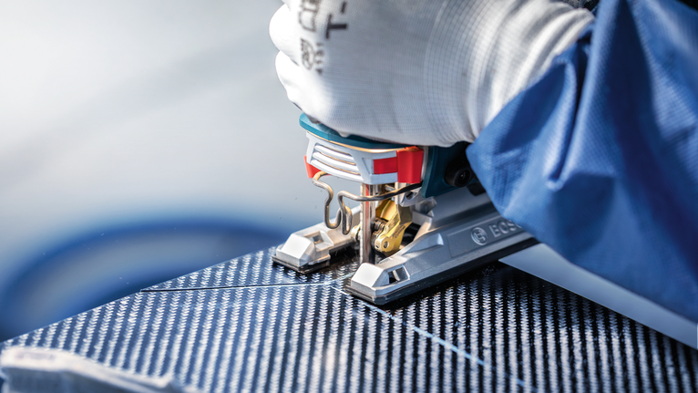 配戴安全設備的人員使用拼圖鋸切割有圖案的面板。.