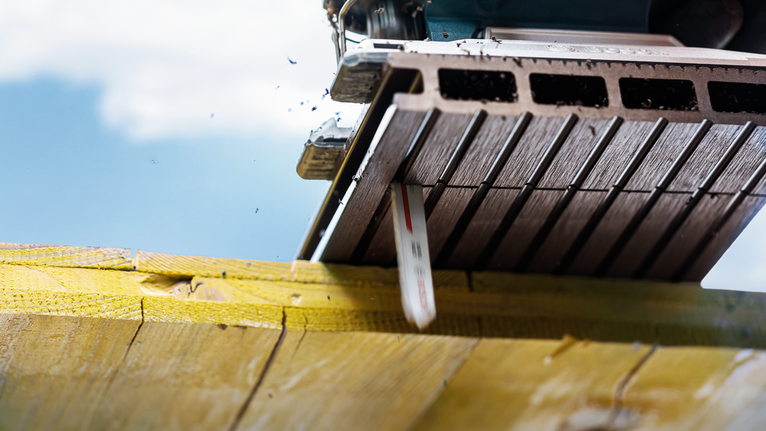 在明亮的室外燈光下，鋸片切割木樑。.