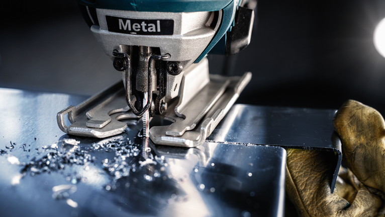 配戴安全設備的人員使用曲線鋸切割金屬板。.