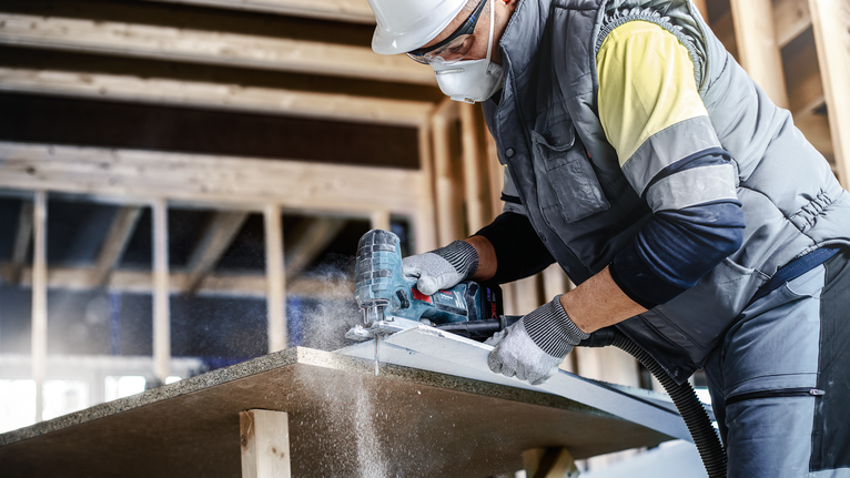 EXPERT ‘Fiber Plaster’ T 141 HM 線鋸片 3 件式 配戴安全設備的人員在施工區域使用電動工具切割木板。.