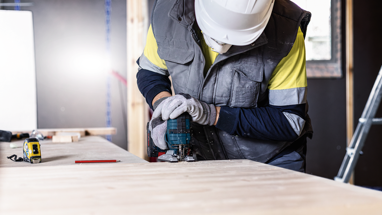 EXPERT ‘Wood 2-side clean’ T 308 B 線鋸片 5 件式 配戴安全設備的人員使用電動工具在工作台上切割木材。.