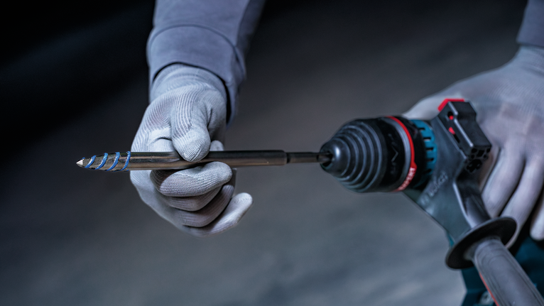 配戴安全設備的人員將鑽頭插入電動工具。