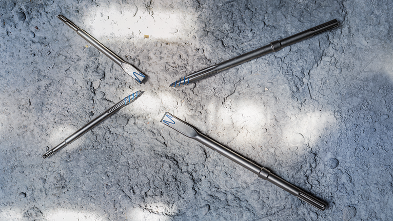 四個金屬鑽頭排列在粗糙的混凝土表面上。