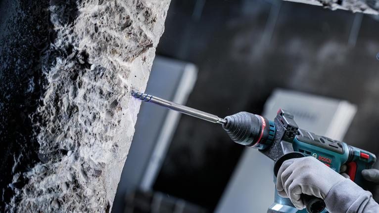 一名佩戴安全設備的人正在鑽入混凝土牆。