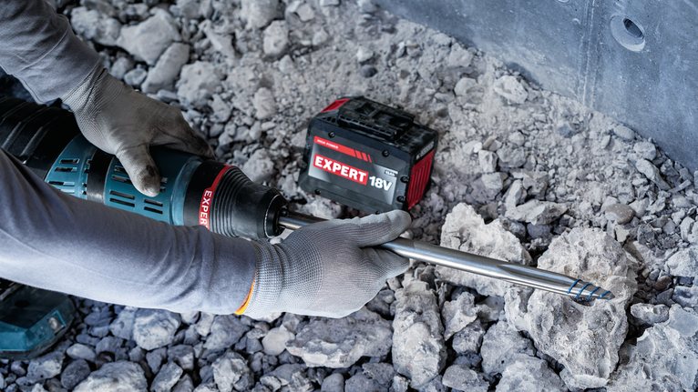 配戴安全設備的人員使用旋轉錘鑽入混凝土碎石中。