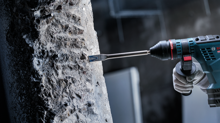 配戴安全設備的人員使用旋轉錘鑿碎混凝土。