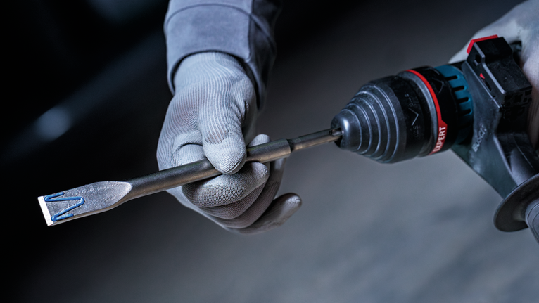 配戴安全設備的人員手持裝有鑿子鑽頭的旋轉錘鑽。