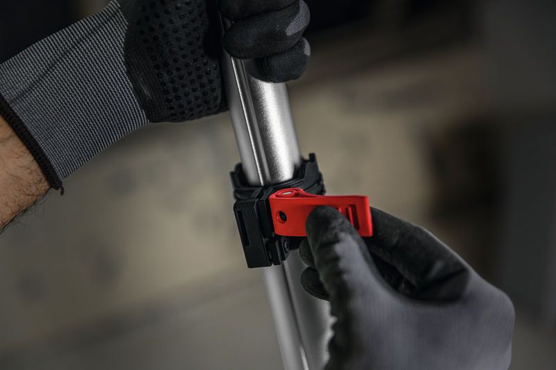 一名穿戴安全裝備的人員正在調整金屬桿上的紅色夾子。