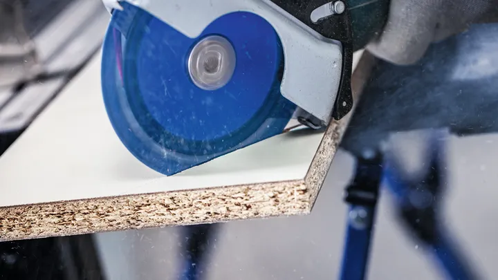 配戴安全設備的人員用圓鋸切割木板。